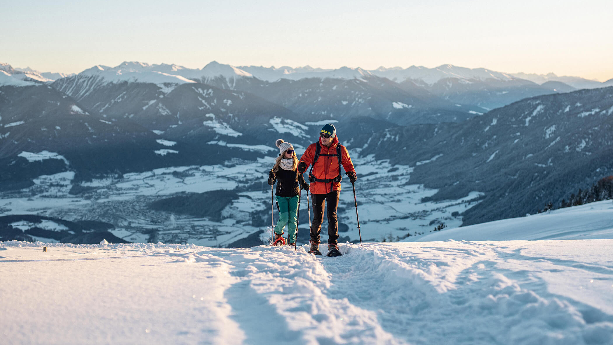 Zwei Schneeschuhwanderer im Neuschnee, im Hintergrund die Südtiroler Berglandschaft - Oberplunerhof