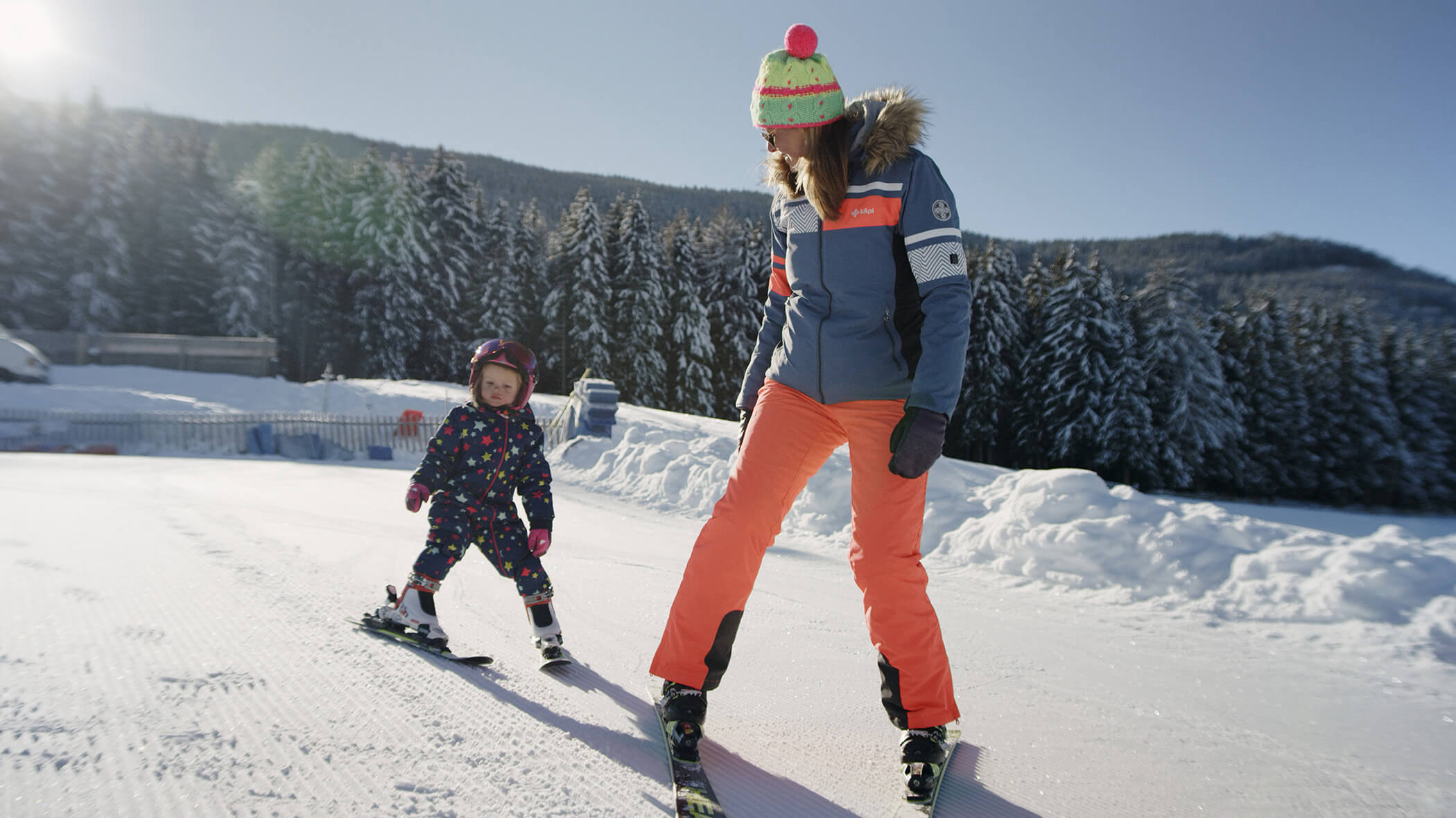 Frau schaut ihrer Tochter beim Skifahren lernen zu - Oberplunerhof