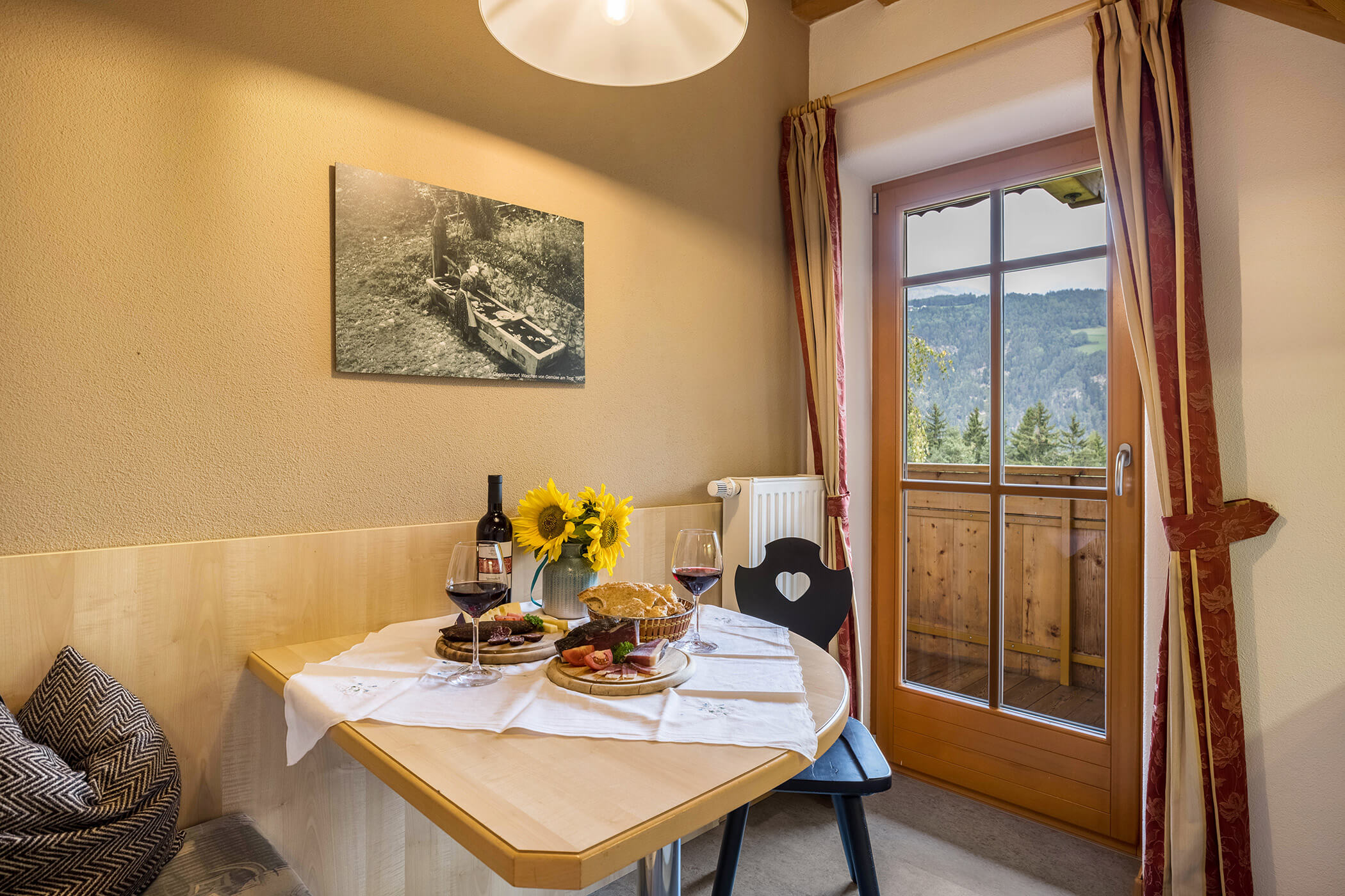 Dining table with wine and South Tyrolean specialties with a view of the balcony in Apartment Brunico - Oberplunerhof