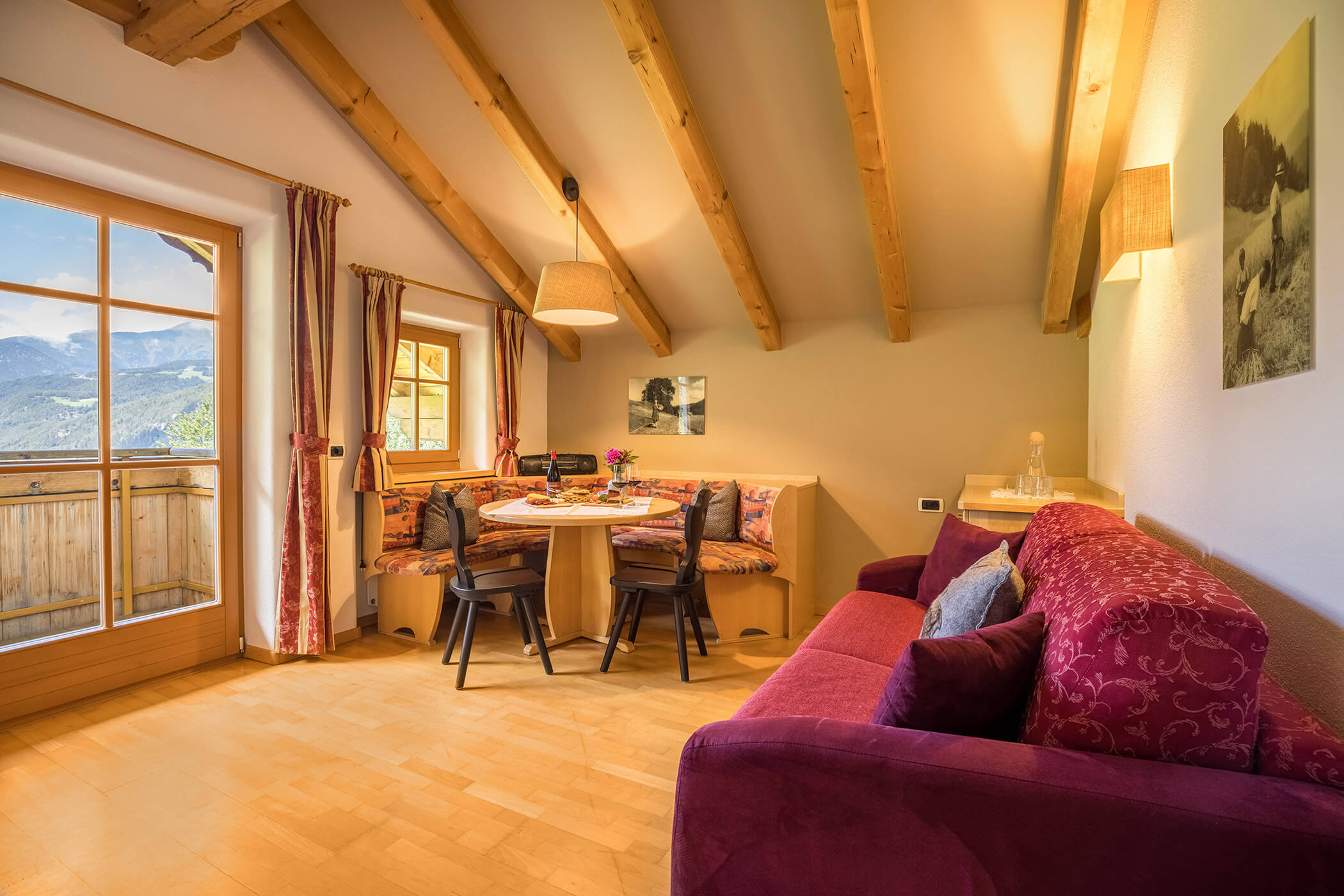 Living room with red sofa, corner bench and table in the Gitschberg apartment - Oberplunerhof
