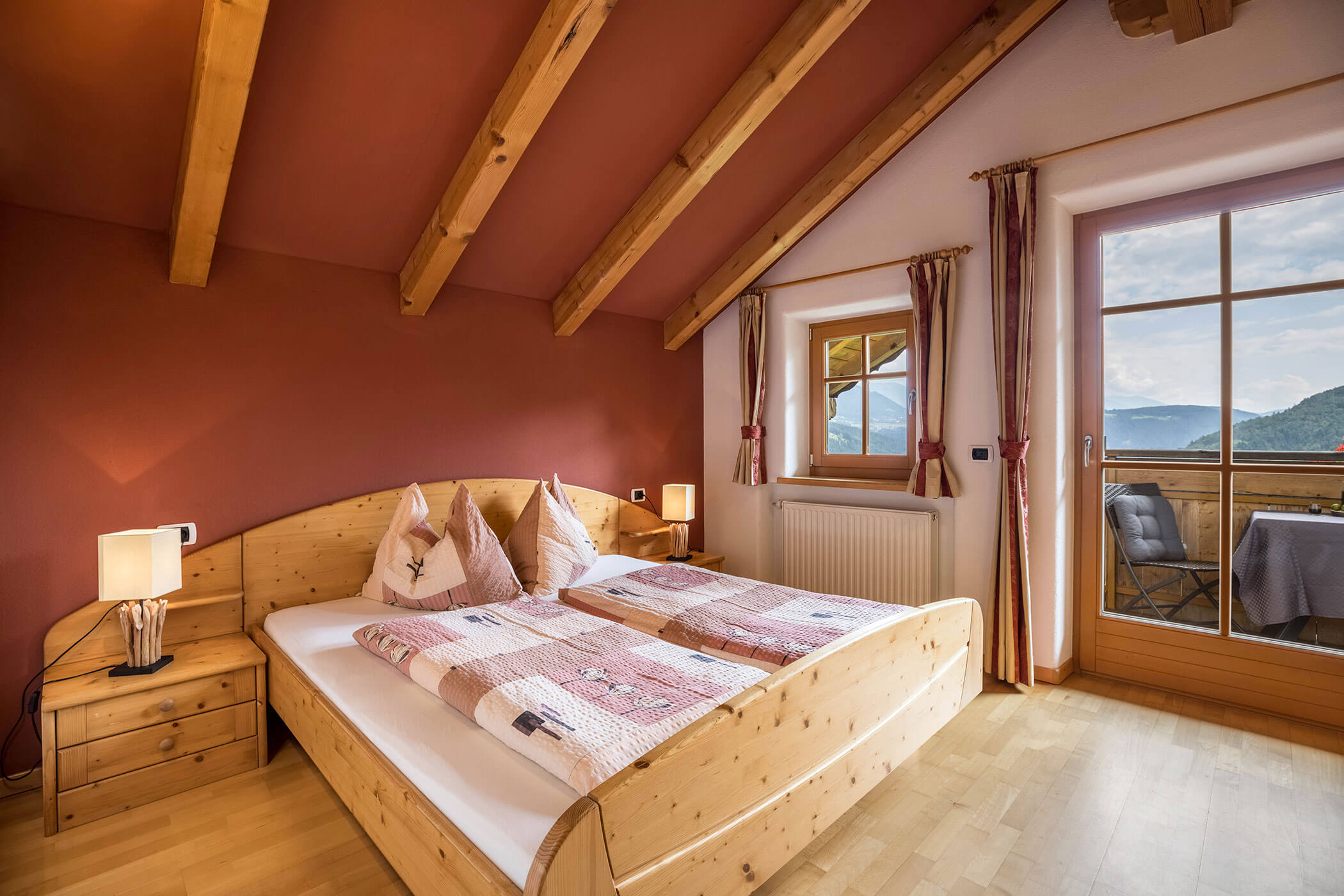 Bedroom in Apartment Brunico with double bed and view of the balcony with table and chairs - Oberplunerhof