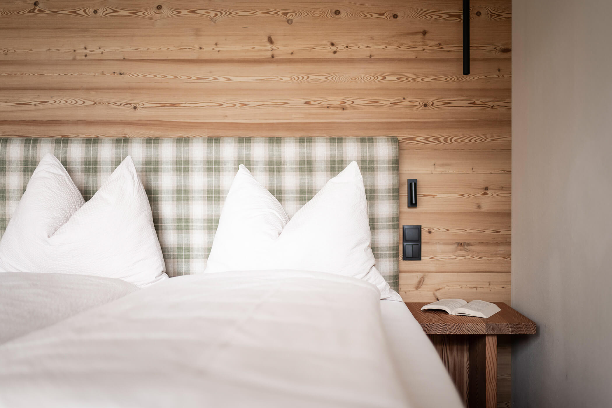 Bedroom in Chalet Woods with bedside table and a book - Oberplunerhof