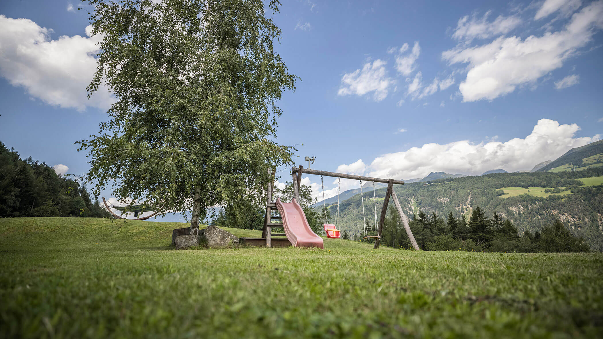 Piccolo parco giochi con due altalene e uno scivolo su un prato con una splendida vista - Oberplunerhof