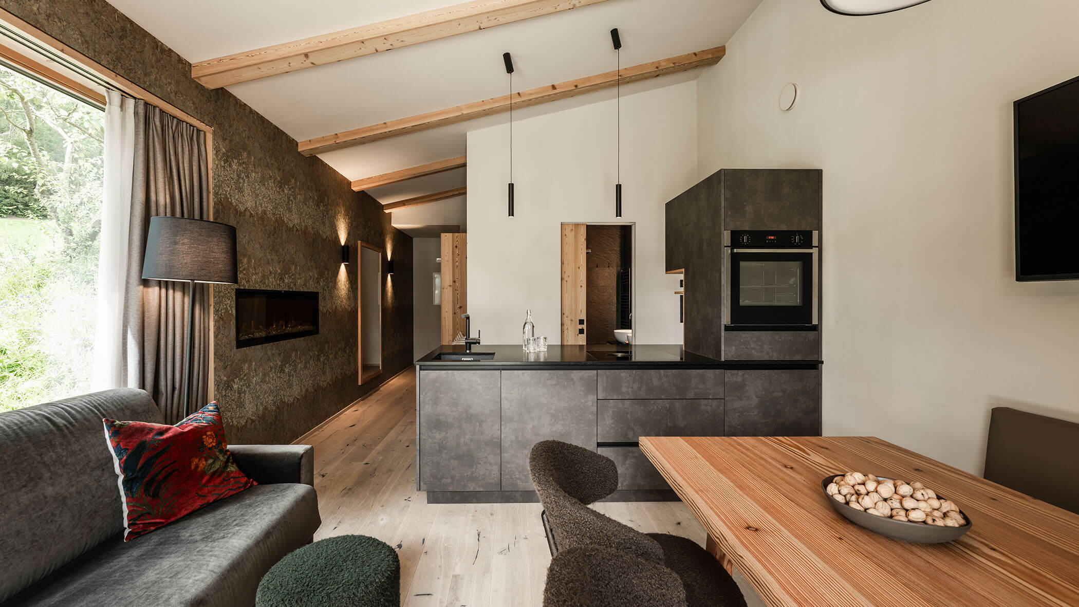 Modern eat-in kitchen with dark kitchenette, sofa and light dining table - Oberplunerhof