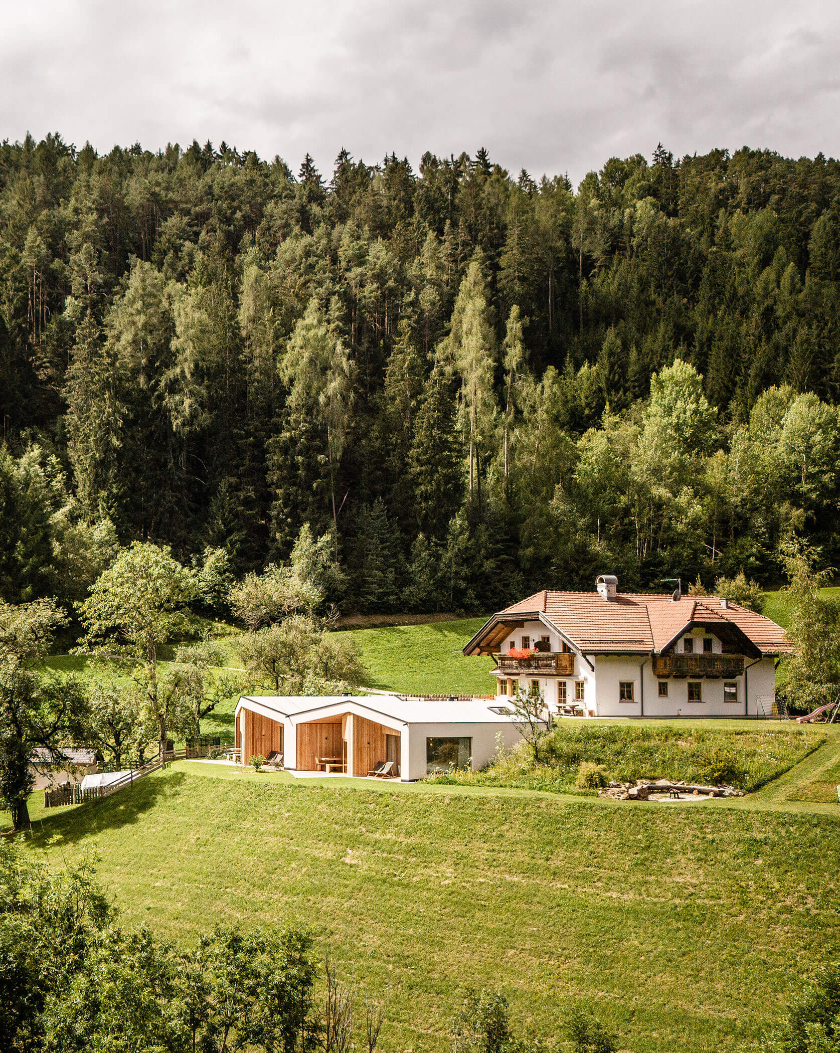 Der Oberplunerhof mit den Chalets von außen, im Hintergrund grüne Bäume und Wiesen - Oberplunerhof