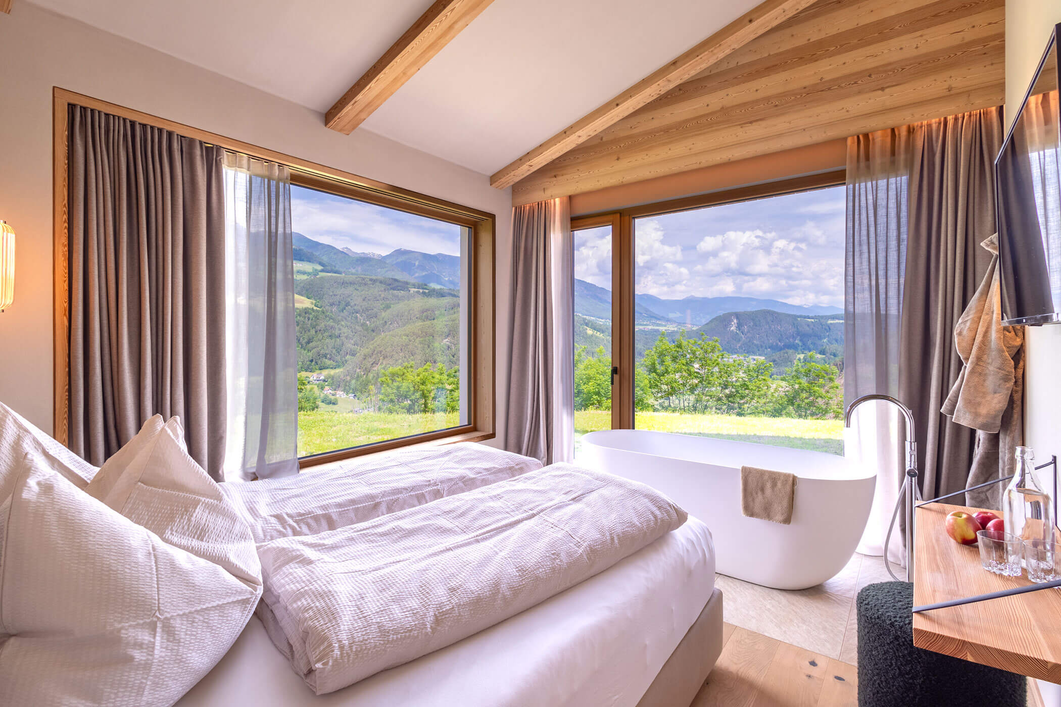Double bed in Chalet Skyline with free-standing bathtub, TV on the wall and magnificent view of the South Tyrolean mountains - Oberplunerhof