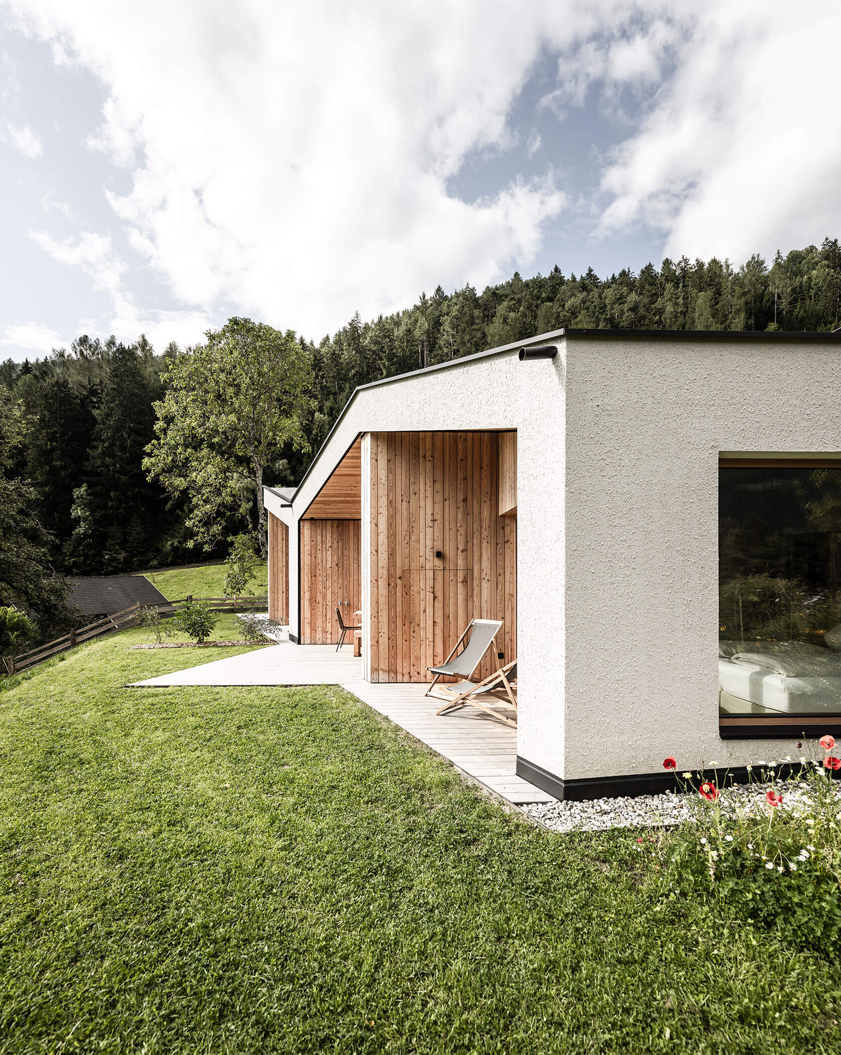 The terraces of the Skyline and Woods chalets with deckchairs and green meadow - Oberplunerhof