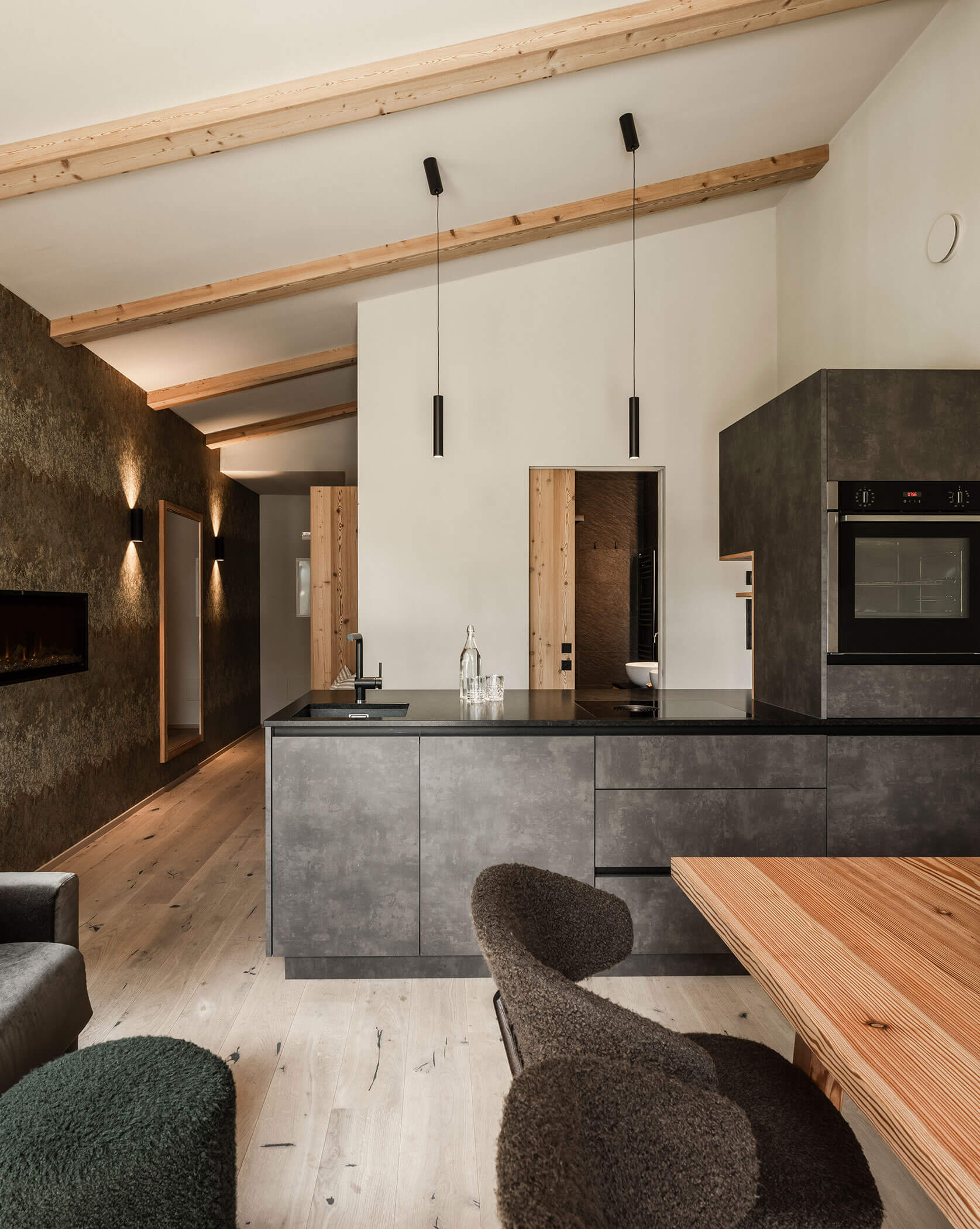 Modern eat-in kitchen with dark kitchen unit, sofa and light dining table - Oberplunerhof