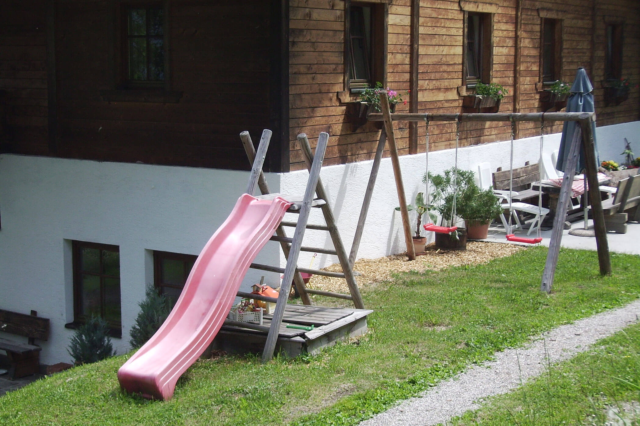 Small playground with two swings, slide and a small sandpit in front of the farm Oberplunerhof