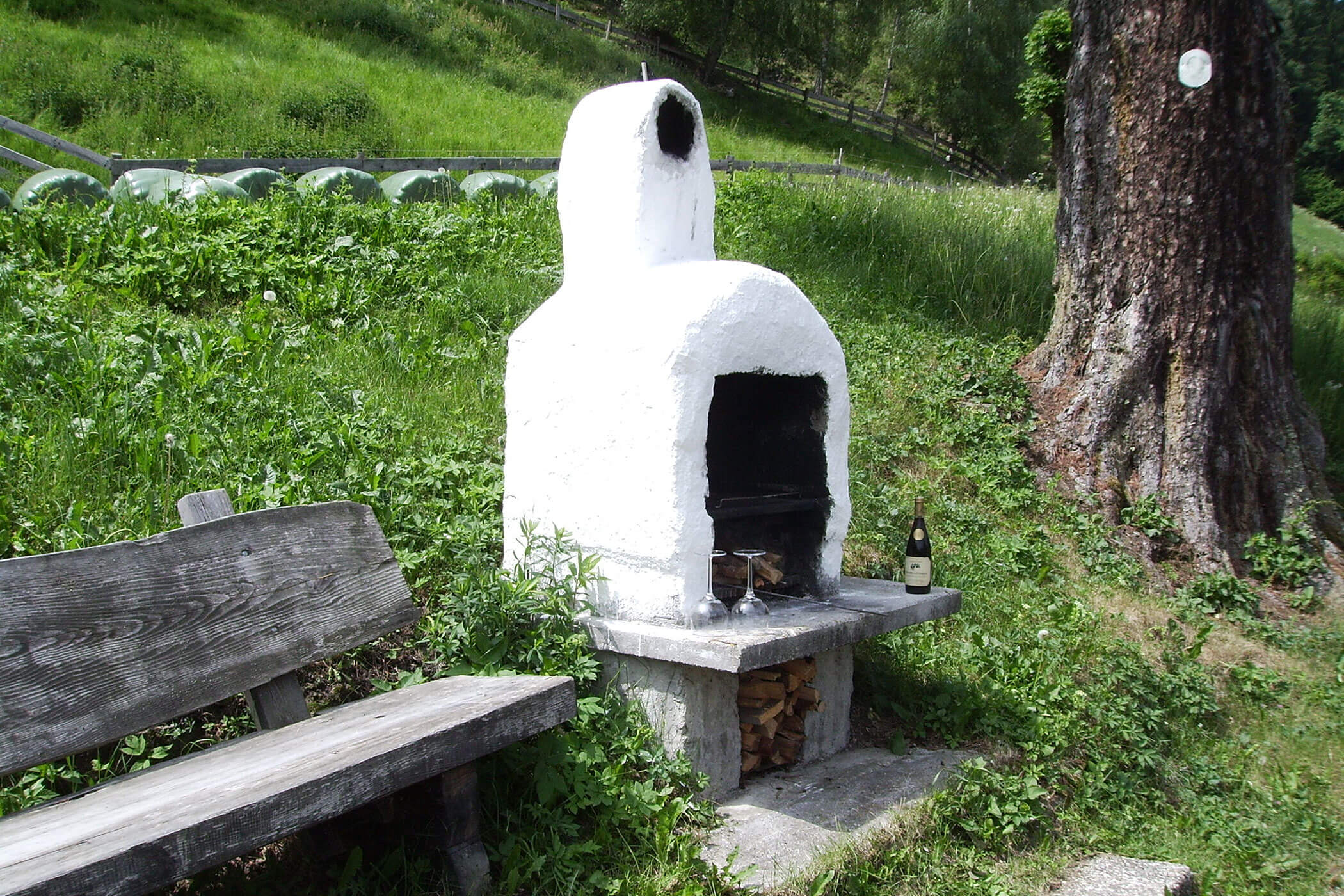 Old barbecue with a wooden bench next to it - Oberplunerhof
