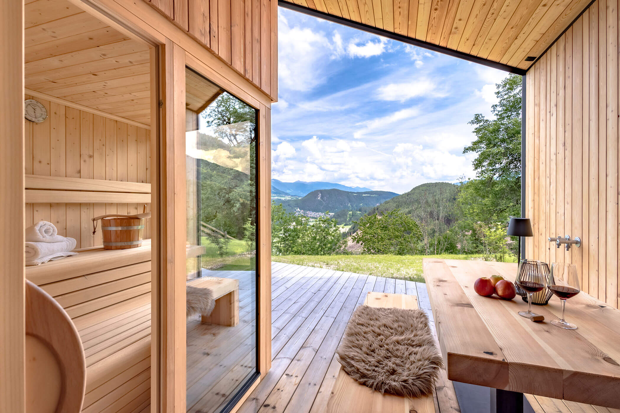 Outdoor sauna with a bench and a table with two glasses of red wine in Chalet Woods - Oberplunerhof