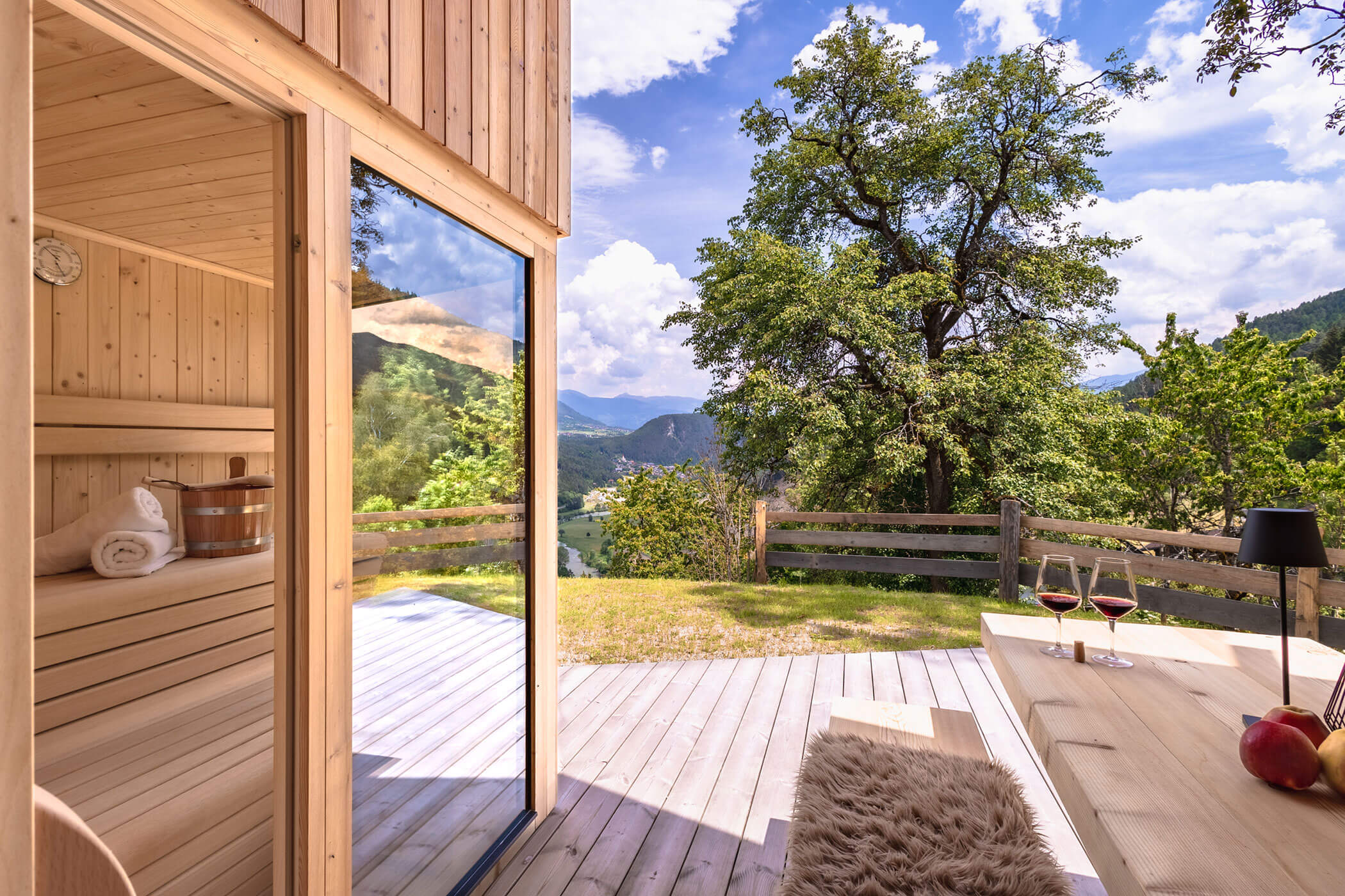 Outdoor sauna with a bench and a table with two glasses of red wine in Chalet Woods - Oberplunerhof