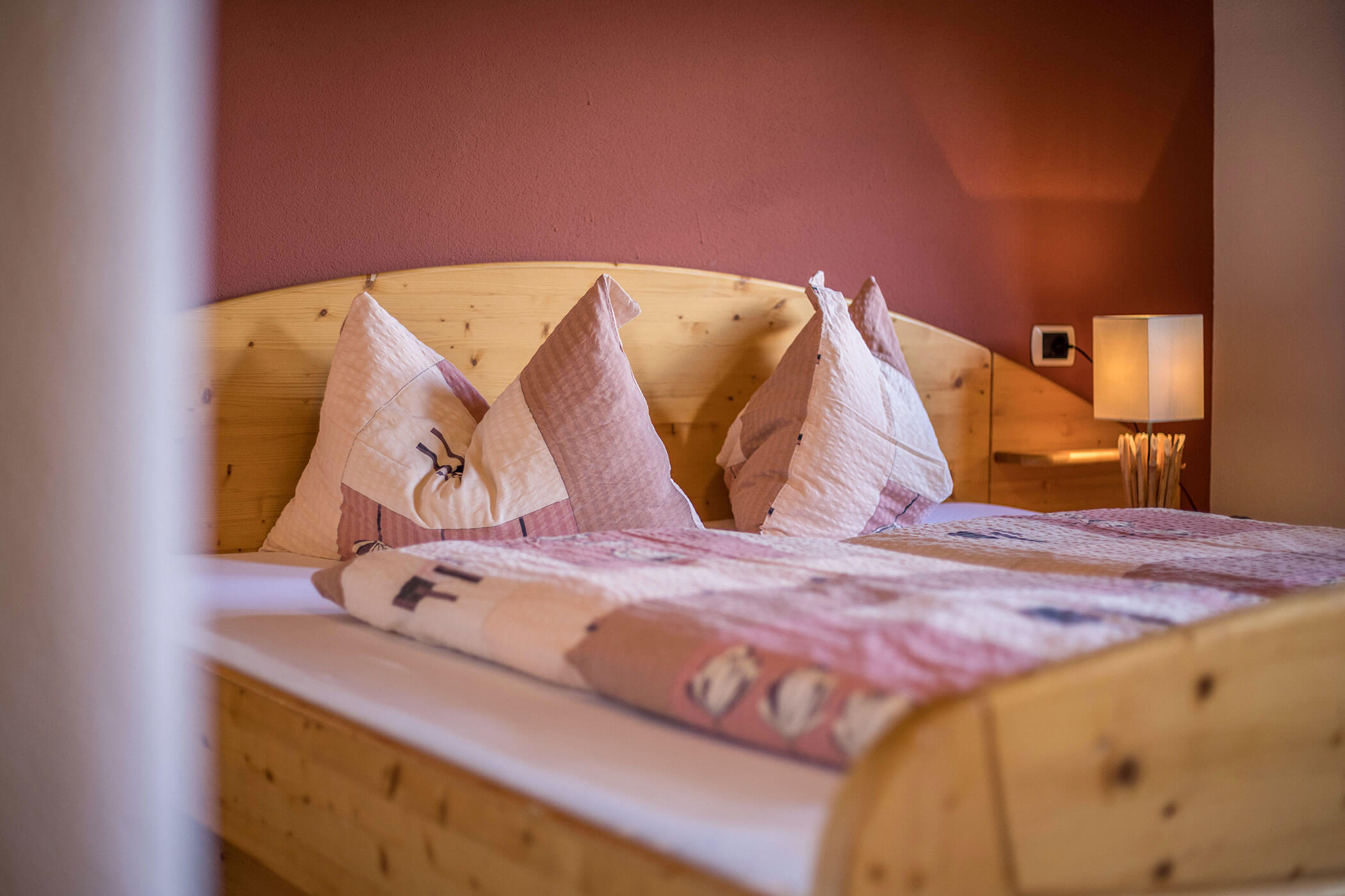Double bed in a vacation apartment at the Oberplunerhof with cozy lighting