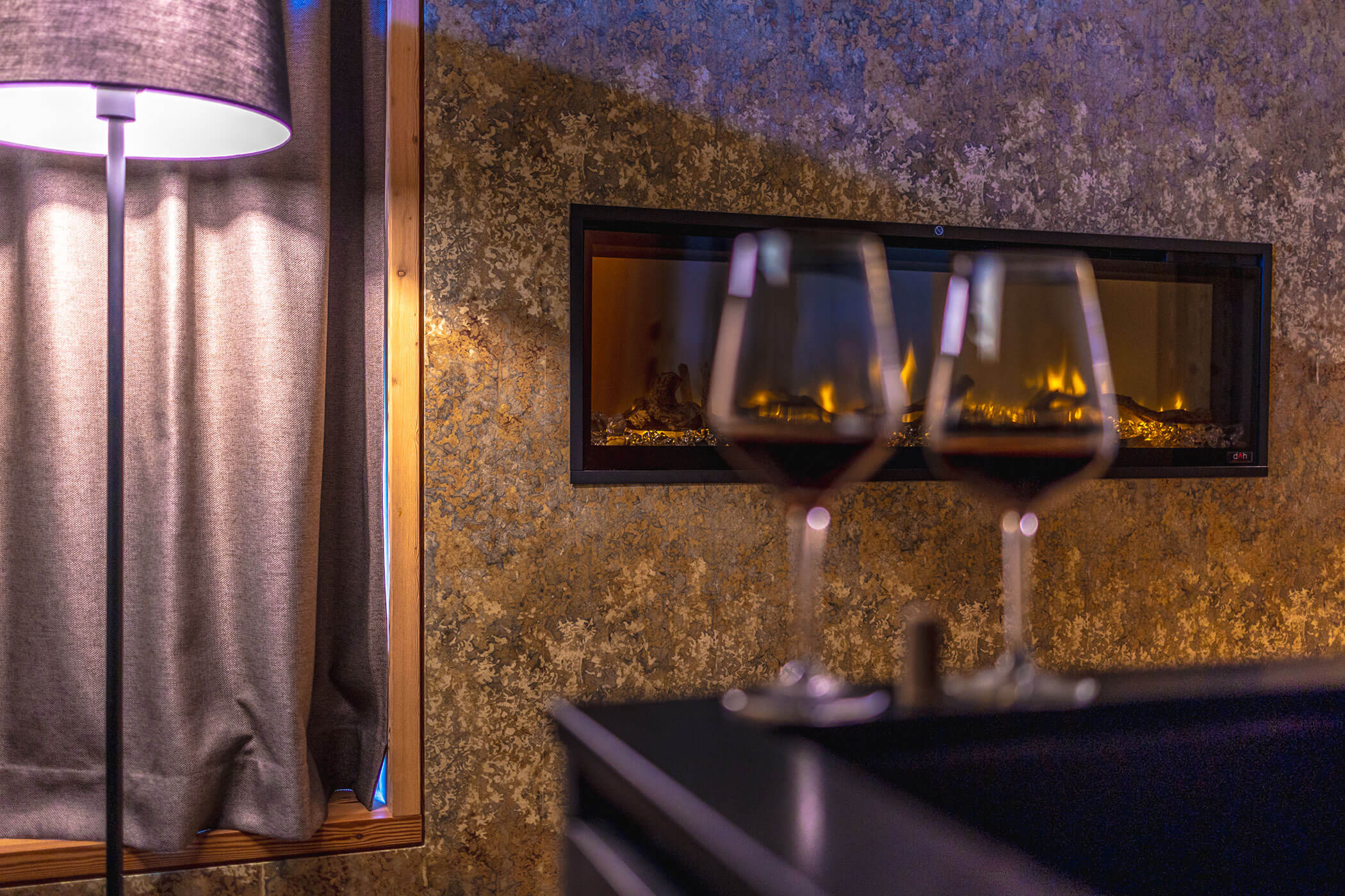 Two wine glasses in front of a fireplace - Oberplunerhof